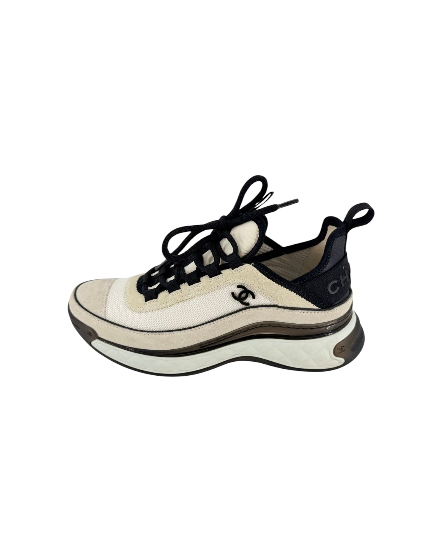 A Chanel chunky sneaker in off-white and black, featuring the iconic interlocking CC logo on the side and a thick wavy sole, shown against a plain white background.